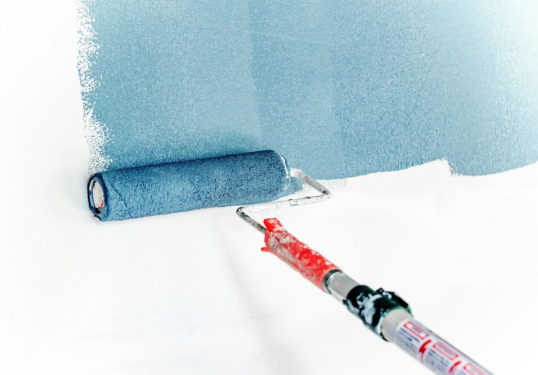 Maler streicht Wand mit Farbrolle